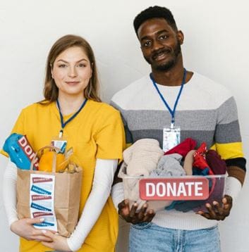 Young adult white female and young adult black male each holding a bag of either groceries or clothing.