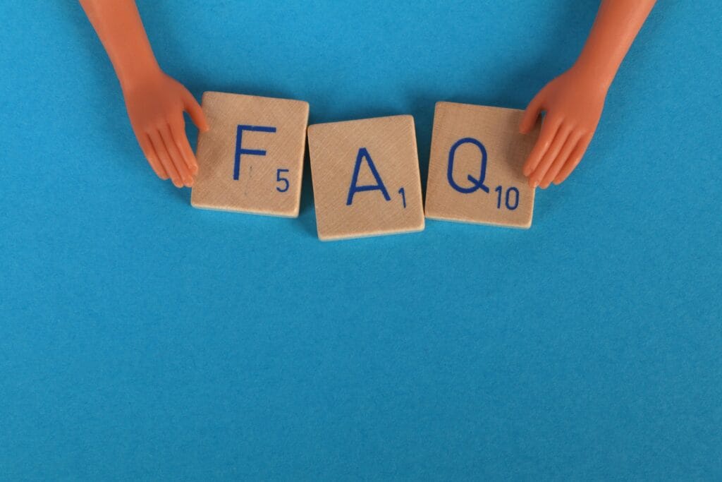 pexels-photo-2789781-2789781 Frequently Asked Questions: Flat lay of scrabble tiles spelling 'FAQ' with toy hands on a blue background, creating a conceptual image.