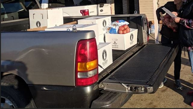 st-james-angel Our Community Partners and Free Rural Food Pantries in Texas: Pick-up truck bed with boxes of food for the needy with volunteers looking at a list of food.