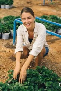 A cheerful woman tending to plants, showcasing joy in gardening and outdoor care.