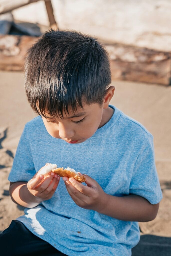 Young male hispanic child with blue short sleeve shirt on eating a biscuit